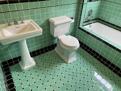 Period pedestal sink installed in green tile bathroom